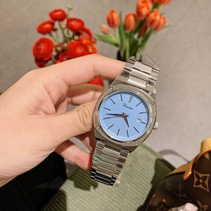 Detail shot of a silver metal watch featuring a blue dial with a functional calendar display
