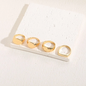 Detailed view of four geometric gold rings with polished finish on stone display