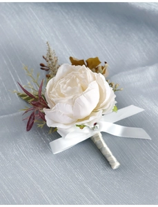 Detail of white artificial rose boutonniere with satin ribbon and rhinestone on blue fabric