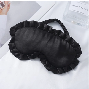 Makro-Detail der schwarzen Satin-Schlafmaske mit Rüschenrand und elastischem Band