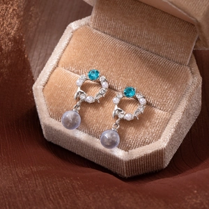 Silver needle earrings with blue stones, pearls, and purple beads in a velvet box