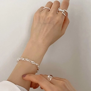 Close-up of minimalist 925 sterling silver woven ring set and chain bracelet on hand