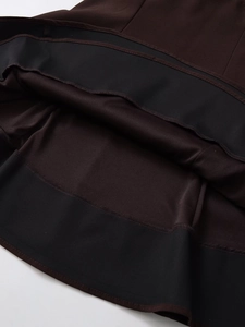 Détail de l'ourlet à double surpiqûre et de la texture du tissu de la robe sombre