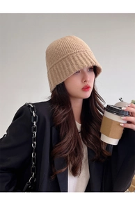 Detailed side view of a beige knitted bucket hat for winter warmth on a female model