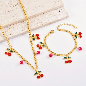 Sweet red cherry jewelry set with gold necklace and bracelet on natural stone background