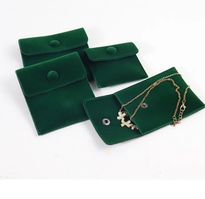 Detailed view of dark green velvet jewelry pouches with snap buttons and flower necklace