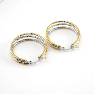 Two-tone gold and silver twisted hoop earrings with hinged clasp on white background