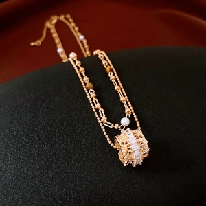 Close-up of double-layer gold necklace with pearls and zircon hollow cylinder pendant