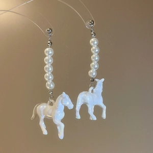Gros plan de boucles d'oreilles avec perles et pendentifs cheval blanc sur supports