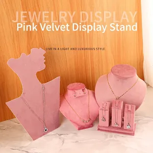 Pink velvet jewelry display set with necklace busts and stands on marble surface