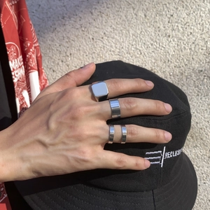 Close-up of a silver metal ring set featuring signet and wide band styles on model hand