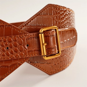 Close-up of brown crocodile texture wide waist belt with a gold rectangular metal buckle