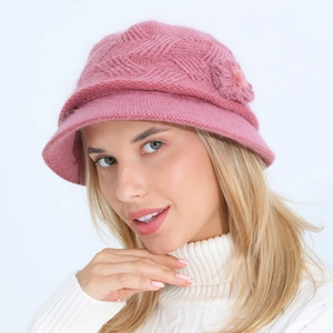 Close-up detail of knitted pink winter hat with floral accent and thick wool texture