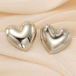 Macro shot of silver heart stud earrings with butterfly back on silk fabric