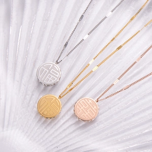 Detail view of titanium necklaces in gold, silver, and rose gold with Fu character pendants