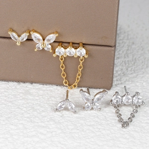 Detail view of butterfly studs and three-stone chain earrings set in gold and silver