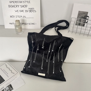 Detailed texture of black velvet tote bag with pearl accents and Suzakka brand label