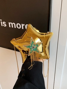 Detail view of gold star-shaped clutch bag with sparkling rhinestone tassels and chain