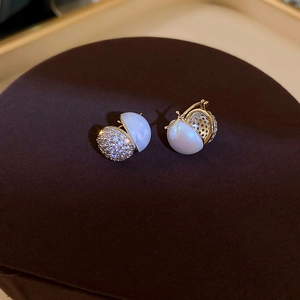 Macro shot of gold-plated hoop earrings with mermaid pearl and zircon stone detailing