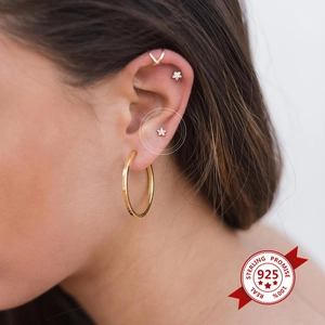 Detail of 925 silver gold star earrings and hoop worn on ear with zircon accents