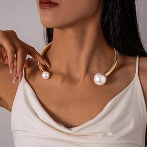Detail of a gold metallic torque choker featuring asymmetric pearls on a textured band