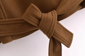 Detailed close-up of a tied belt on a brown wool coat showing premium fabric texture