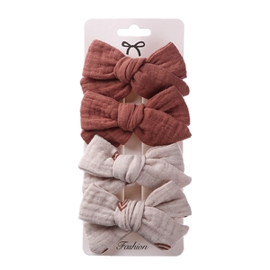 Close-up of four-piece bow hair clip set in beige and terracotta on display card
