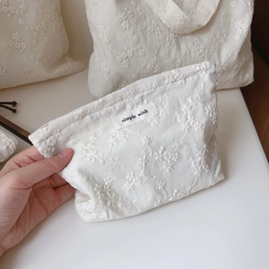 Detailed close-up of beige cotton pouch with floral embroidery and Simple Wish label