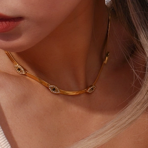 Close-up of 18K gold plated snake chain necklace with sparkling evil eye charms on a model