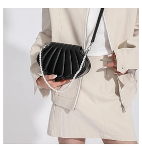Detailansicht einer schwarzen muschelförmigen Handtasche mit Falten und Perlengriff