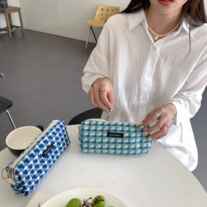 Détail de pochettes en tissu à carreaux bleus avec fermeture éclair et étiquette