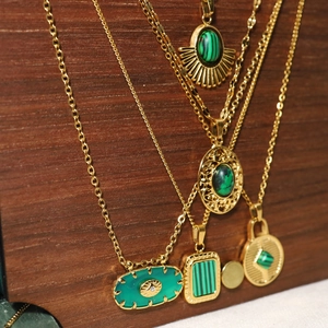 Vue détaillée de colliers en or 18 carats avec pendentifs malachite sur fond en bois sombre