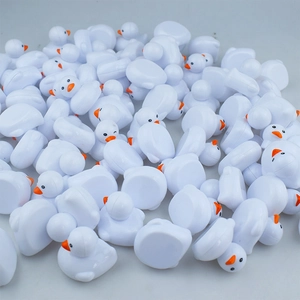 Detailed macro view of bulk miniature white plastic ducks with orange beaks and black eyes