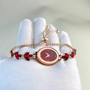 Luxurious gold oval quartz watch with red leaf-shaped gems and matching red dial