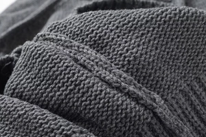 Macro view of dark grey thick knit fabric texture with detailed chunky knit patterns