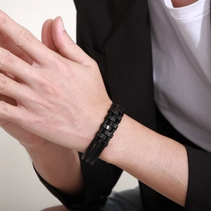 Close-up of men's multi-layer black braided leather bracelet with geometric clasp