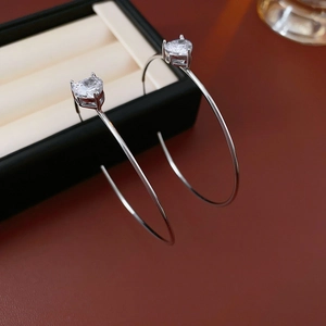 Détail macro de boucles d'oreilles argentées en C avec zircon cœur sur boîte