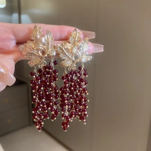 Detail of vintage gold leaf earrings with dark red grape-style bead tassels and highlights