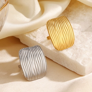 Textured 18K gold plated rectangular stainless steel ring on a white stone base