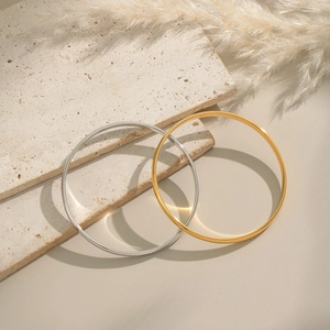 Elegant minimalist stainless steel bangles in gold and silver finish on stone tray