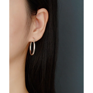 Close-up of minimalist 925 sterling silver hoop earring on model with black hair backdrop