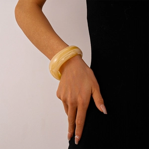 Close-up of wide amber resin cuff bracelet with marble texture worn on wrist