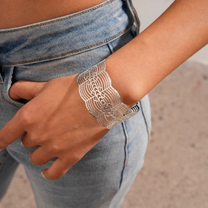 Detailed view of silver open cuff bracelet with complex hollow mesh pattern on model wrist