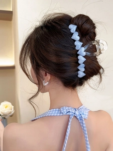 Close-up of large clear resin hair claw clip with blue heart accents on model hair
