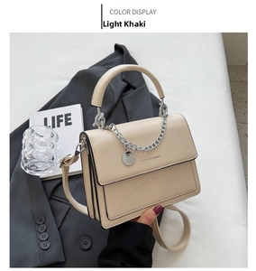 Detail of light khaki fashion crossbody bag with chain strap on a grey blazer