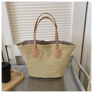Detail of hand-woven straw tote bag with brown leather handles and reinforced stitching