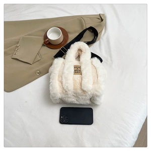 Detail of white plush tote bag showing soft fuzzy texture and black canvas shoulder strap