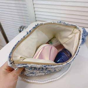 Detailed interior of blue and white tweed makeup bag showing storage space and lining