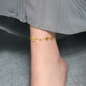 Elegant gold titanium steel anklet featuring multiple daisy flower charms worn on ankle