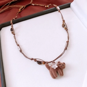 Gros plan sur le collier pendentif chat marron avec perles œil de tigre et cordon